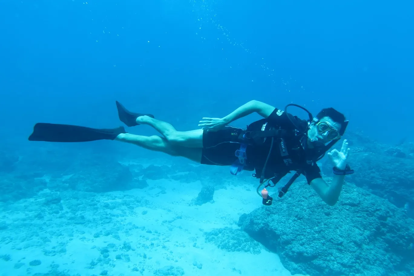 Plongeur de Wulfy Diving au-dessus d’un fond de sable et de roches